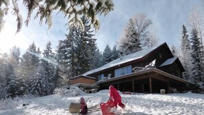 Un paisaje nevado con una cabaña de madera y árboles cubiertos de nieve.
