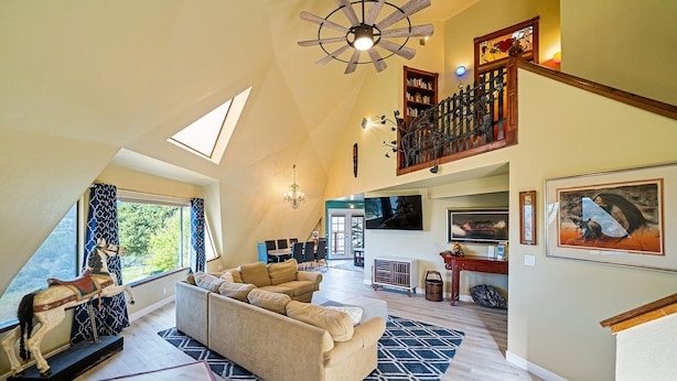A spacious living room with a high ceiling, a large sofa, a horse sculpture, and a staircase leading to an upper level. - Kid Friendly with Breathtaking Views on 10 Acres (Sonoma)
