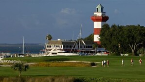 A lighthouse, a building with a balcony, and a golf course with people playing.
