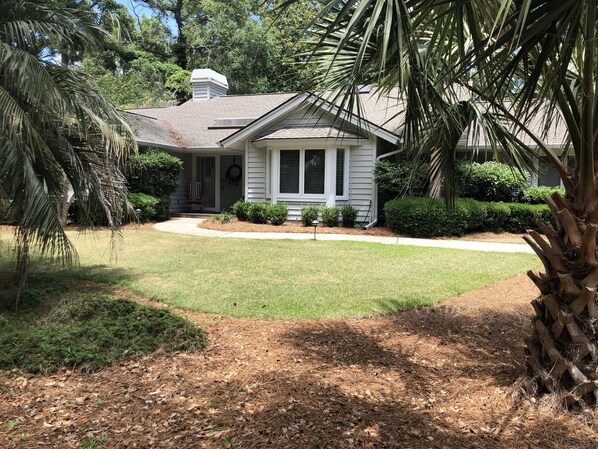 A single-story house with a front porch, surrounded by a well-maintained lawn and various shrubs. - Celebrate at the Beach Thanksgiving! Private Pool and Free Bikes! (Hilton Head Island)