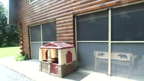 A wooden cabin with a large garage door, a small playhouse, and a bear-themed sign.