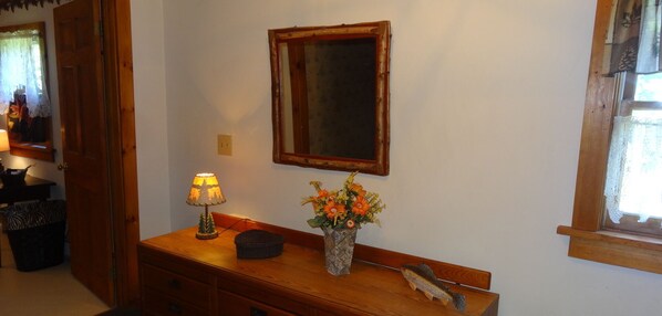 A wooden dresser with a lamp and a vase of flowers.