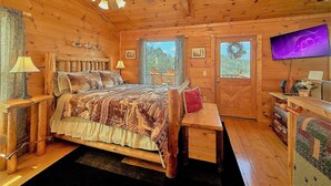 A wooden cabin bedroom with a bed, a desk, a television, and a ceiling fan. - Aug Special-Secluded, Privacy, Mountain View, Sunset, 3D Movies, Hot Tub,Game Rm (Sevierville)