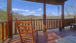 A wooden deck with a wooden rocking chair and a table, overlooking a mountainous landscape. - Aug Special-Secluded, Privacy, Mountain View, Sunset, 3D Movies, Hot Tub,Game Rm (Sevierville)