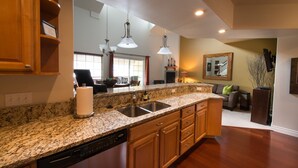 A kitchen with granite countertops, wooden cabinets, a dishwasher, and a large mirror. - Leavenworth Vacation Rental, Luxury , Downtown,  Amazing Mountain View Condo,  (Leavenworth)