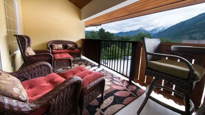 A balcony with wicker furniture, a patterned rug, and a view of mountains. - Leavenworth Vacation Rental, Luxury , Downtown,  Amazing Mountain View Condo,  (Leavenworth)