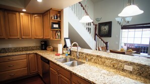 A kitchen with granite countertops, wooden cabinets, a stainless steel sink, and a staircase leading to another level. - Leavenworth Vacation Rental, Luxury , Downtown,  Amazing Mountain View Condo,  (Leavenworth)