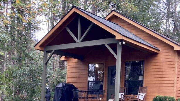 Eine Holzhütte mit Veranda, Sitzgelegenheiten im Freien und einem Feuerkorb.