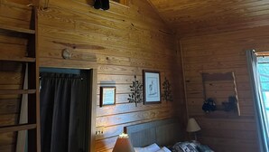 Ein Holzblockbau-Innenraum mit Treppe, Deckenventilator und einem Bett.
