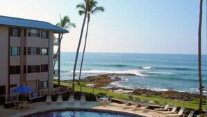 A hotel with a pool, lounge chairs, and a view of the ocean.