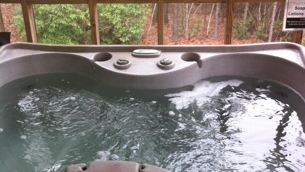 A hot tub with a view of a forest through large windows. - Hawk's Nest Hideaway With Creek That Runs Through This Very Private Property (Mentone)