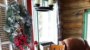 Interior acogedor de una cabaña de madera con comedor que incluye una mesa con mantel de cuadros, sillas de madera y un sofá de cuero.