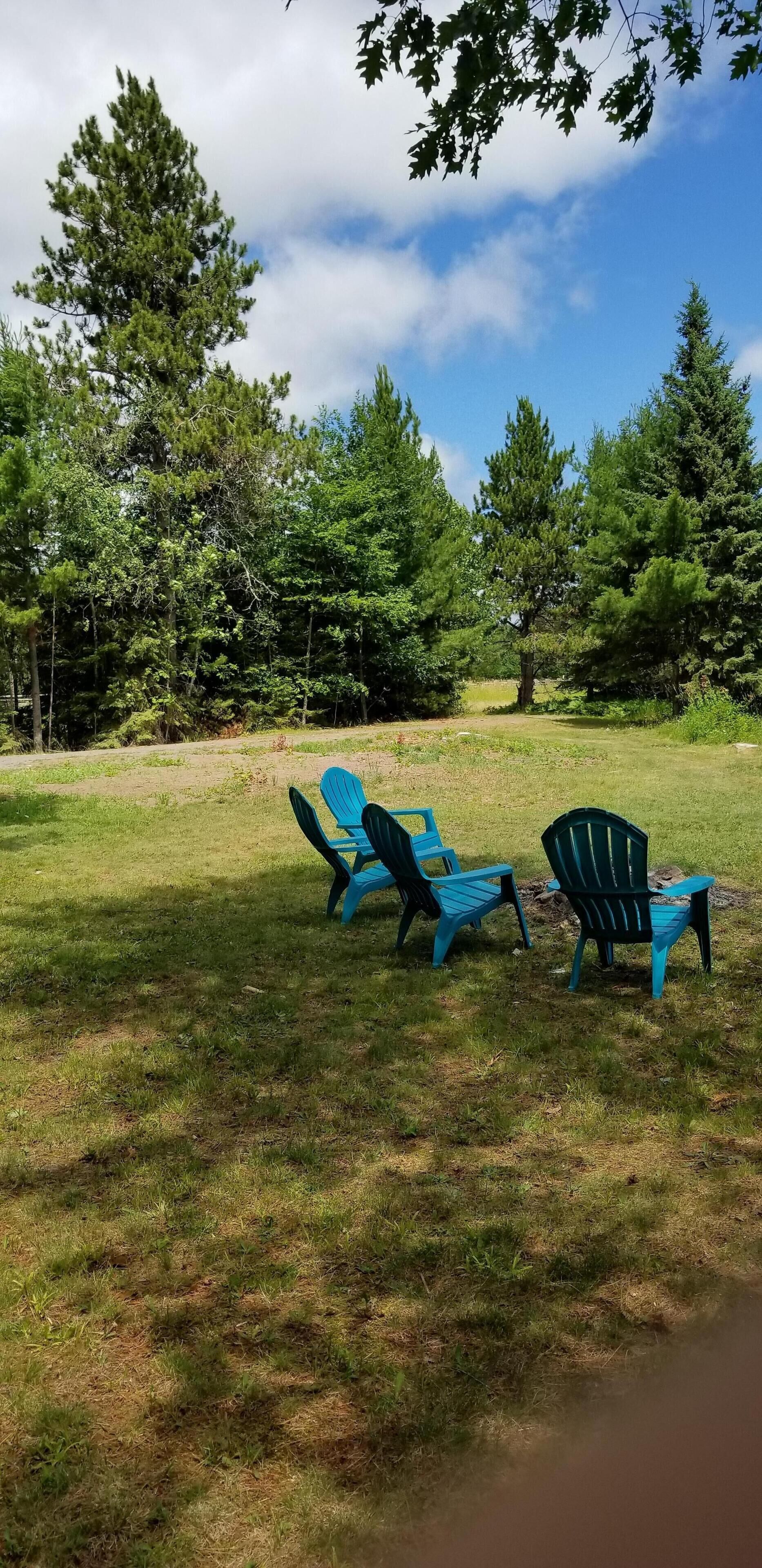 Een gazon met twee blauwe Adirondack stoelen en een picknicktafel.