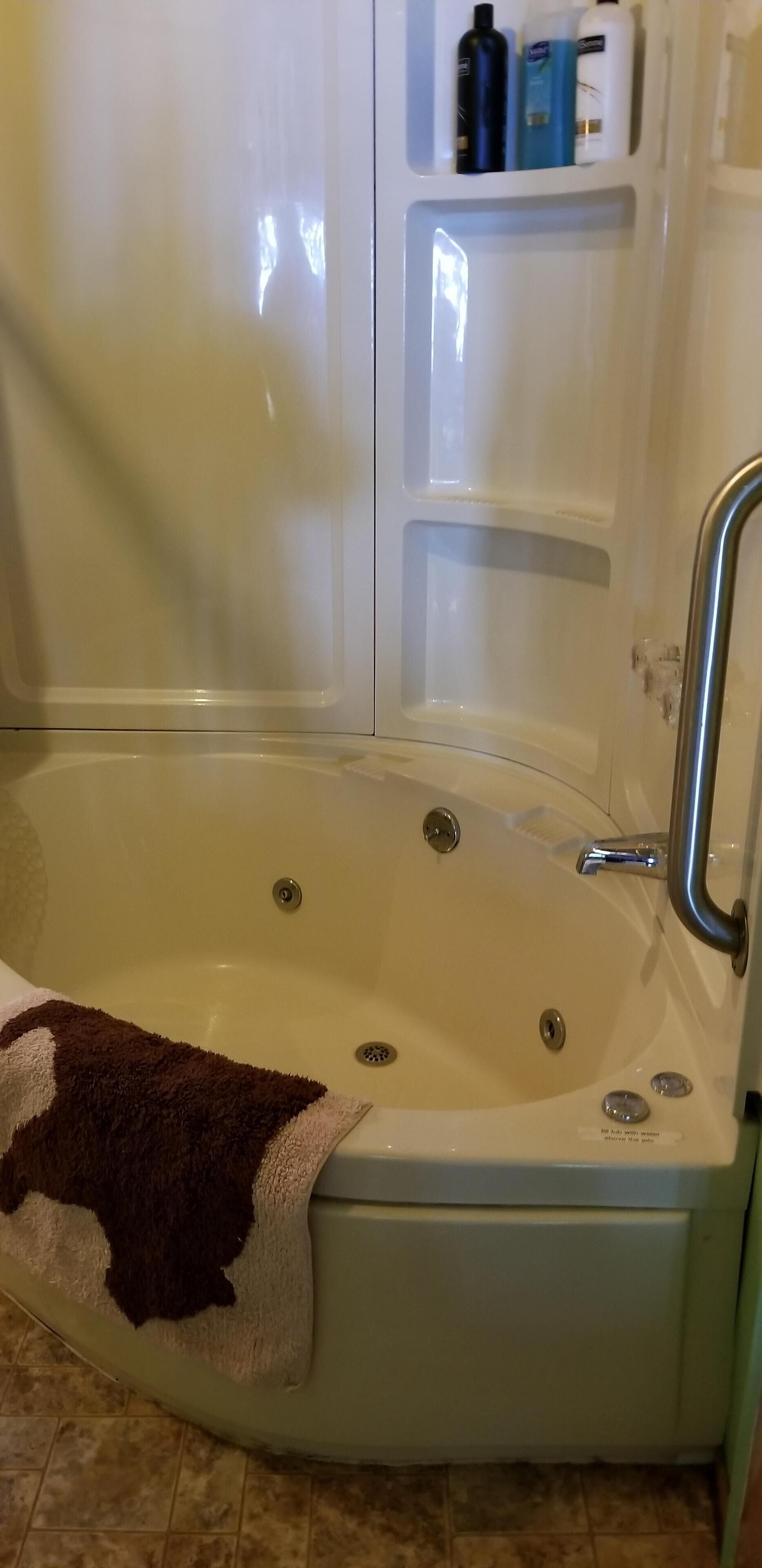 A bathtub with a towel, a shelf with toiletries, and a shower area.