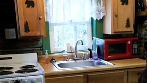 Una cocina con armarios de madera, estufa, fregadero y microondas.
