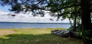 Une vue sur le lac, avec un bateau et une chaise près d’un arbre.