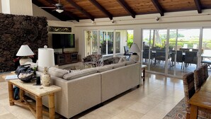 A spacious living area with a large sofa, a TV, and a stone wall.