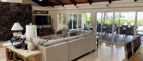 A spacious living area with a large sofa, a TV, and a stone wall.