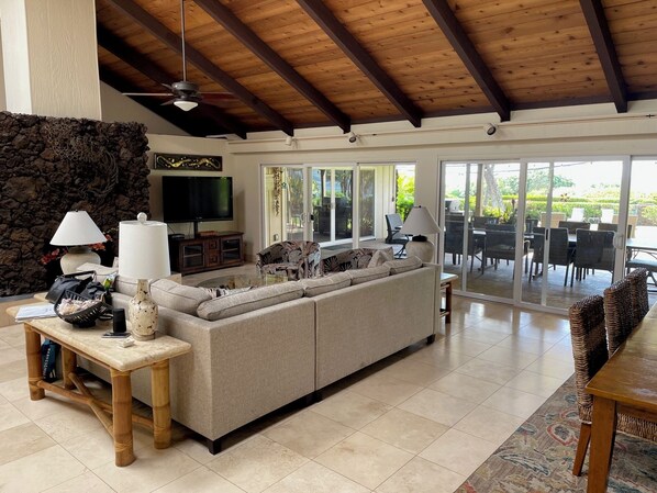 A spacious living area with a large sofa, a TV, and a stone wall.