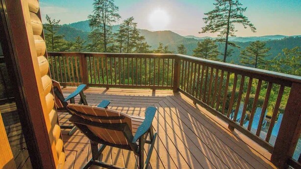 Terraza de madera con dos mecedoras que da a un paisaje montañoso.