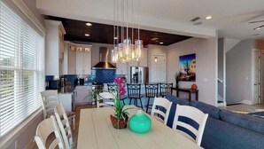 A modern kitchen with white cabinets, a blue backsplash, and a hanging light fixture.