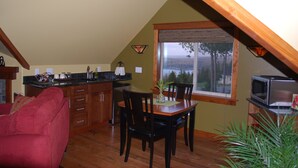 A kitchen with wooden cabinets, a dining table with chairs, a red couch, and a view through a window. - "THE LOFT" romance, luxury, stunning water and mountain views!   (Sequim)