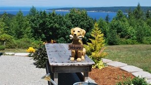 A wooden bench with a 'Welcome' sign and a dog figurine. - "THE LOFT" romance, luxury, stunning water and mountain views!   (Sequim)