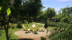 Un espace patio avec des sièges extérieurs et une vue sur un jardin aménagé.