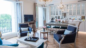 A spacious living room with a balcony, a dining area, and a kitchen with white cabinets.