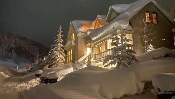 Une maison recouverte de neige, dotée d’un porche et d’un escalier menant à l’entrée.