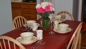 Ein Esstisch mit Geschirr mit Blumenmuster und einer Blumenvase.