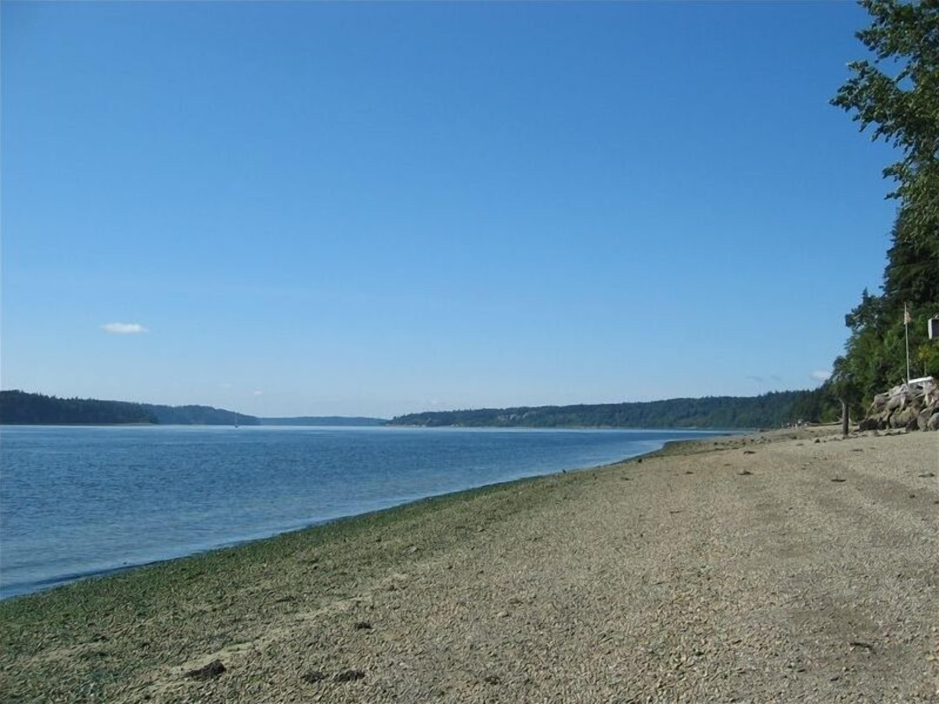 A beach with a clear view of the water and distant land.