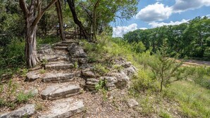 Una escalera de piedra que asciende por una colina, rodeada de árboles y vegetación.