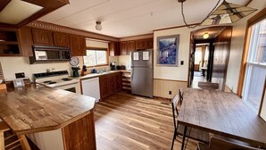 Een keuken met houten kastjes, een roestvrijstalen koelkast en een eethoek met een houten tafel en stoelen.