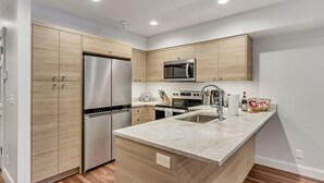 A modern kitchen with wooden cabinets, stainless steel appliances, and a marble countertop. - Ski-in/Ski-Out, Walk to Main St. Clean, Spacious, REMODELED,  Arts Festvl. A/C (Park City)
