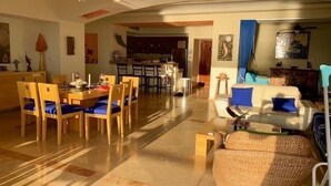 Amplia sala de estar con una mesa de comedor y sillas, un sofá y una silla de mimbre.