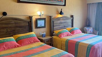 A hotel room with two beds, a wall hanging, a nightstand, and a lamp.