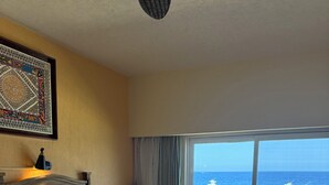 Habitación de hotel con dos camas, un ventanal con vista al océano y un ventilador de techo.