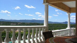 A balcony with white balustrades overlooking a mountainous landscape.