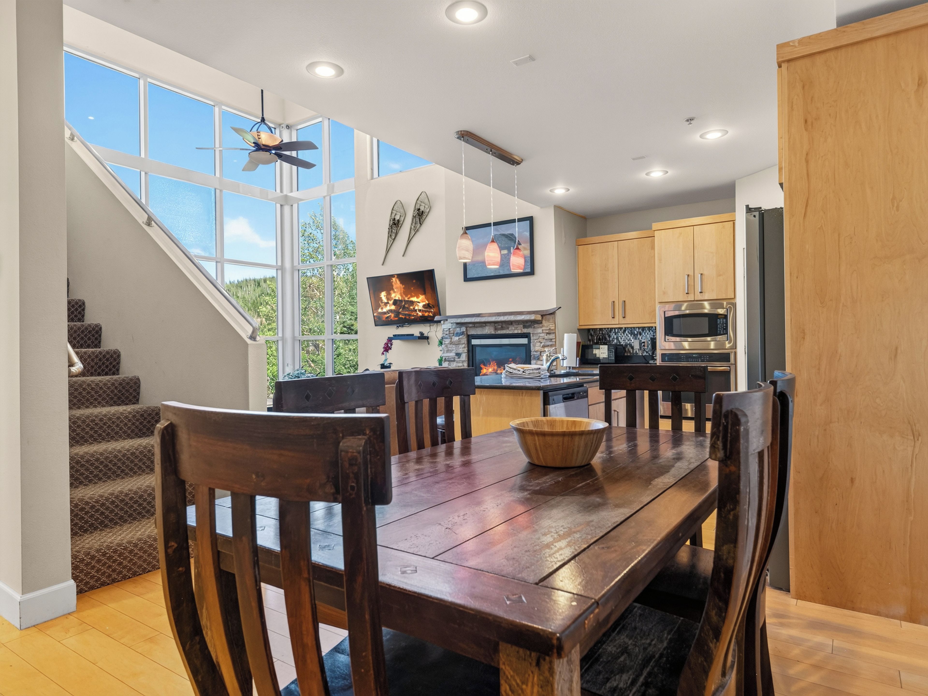A modern kitchen with a dining area, wooden furniture, and a fireplace.