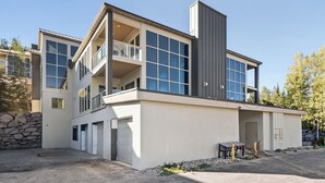 Een modern huis met twee verdiepingen, een garage, een balkon en een stenen muur.