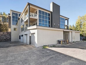 Ein modernes, zweistöckiges Haus mit Garage, Balkon und einer Steinmauer.