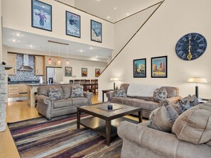 A spacious living area with a kitchen, dining area, and a large clock on the wall. - Magic Carpet 2 bdrm 2 bth plus game loft walking distance to Giant Steps Lifts (Brian Head)