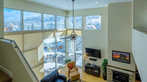 A spacious living area with a fireplace, large windows, and a television.