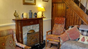 A traditional room with a fireplace, a wooden staircase, and a patterned rug.