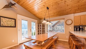 A spacious kitchen with wooden countertops, a large wooden table, and a hanging light fixture.