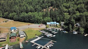 A marina with docks and boats, surrounded by dense forest and a mountain in the background.