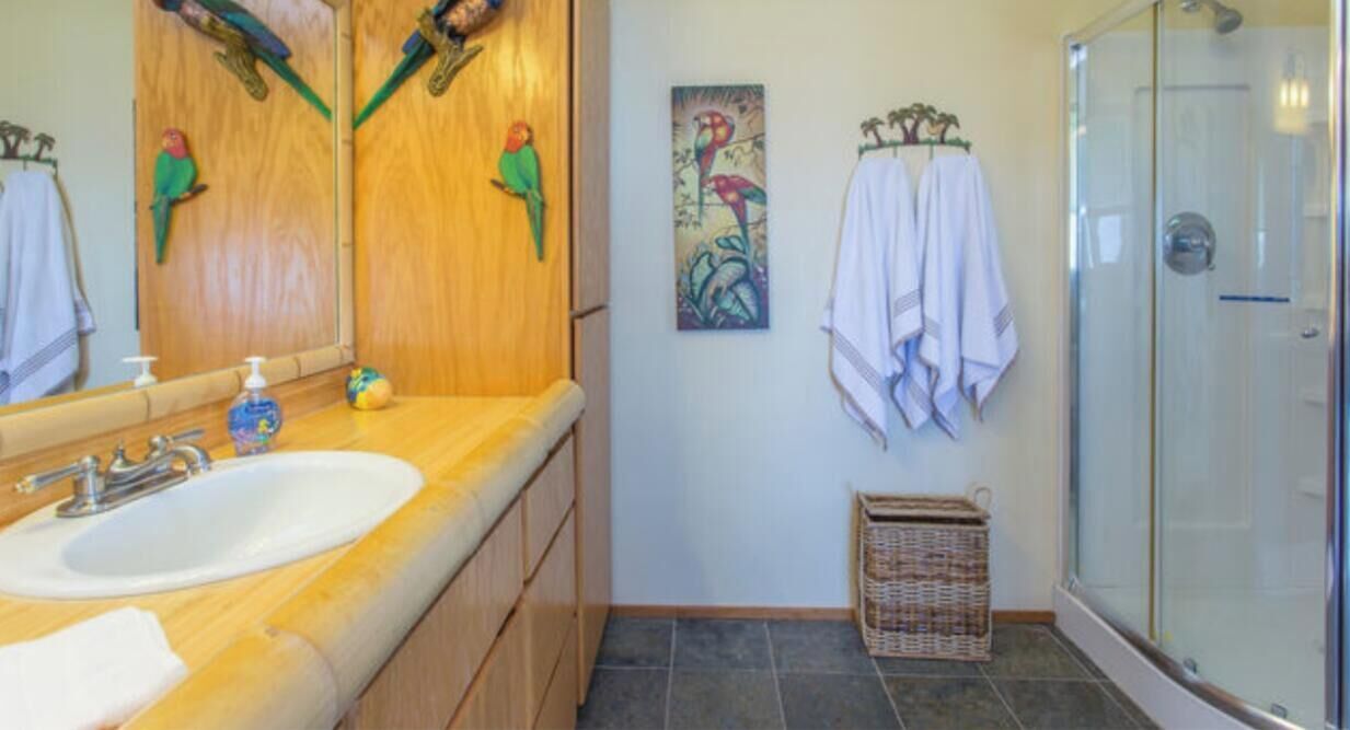 A bathroom with wooden cabinets, a sink, a glass shower, and a wall-mounted towel rack.