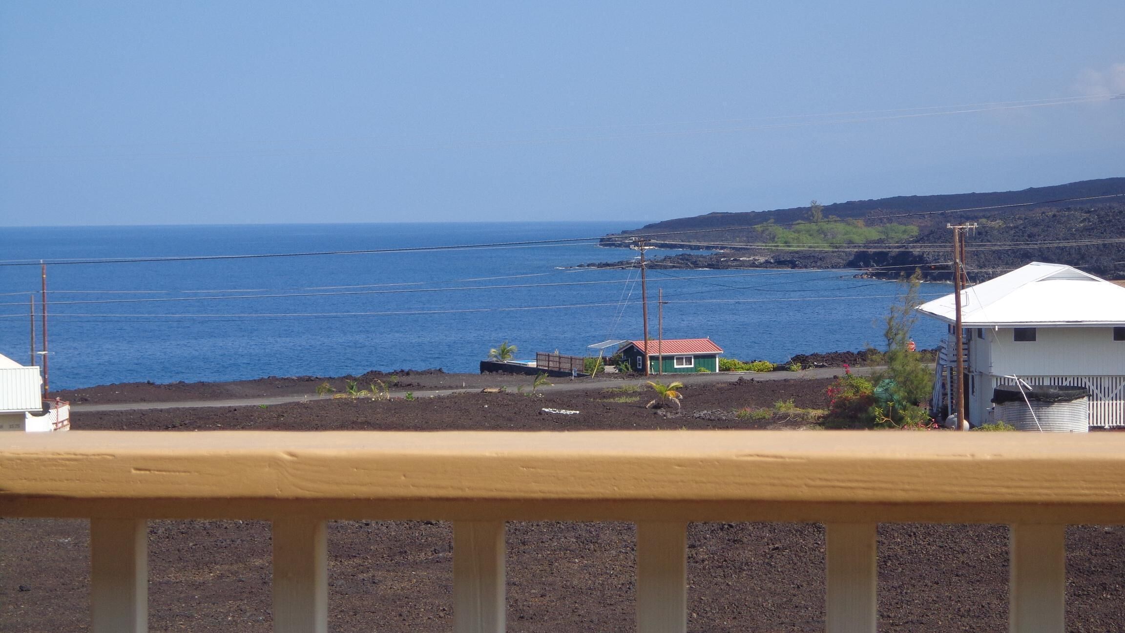 Une vue sur la côte, avec une petite maison et un bâtiment blanc, tous deux coiffés de toits rouges, qui dominent l’océan.