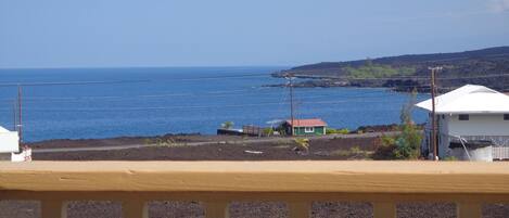 Une vue sur la côte, avec une petite maison et un bâtiment blanc, tous deux coiffés de toits rouges, qui dominent l’océan.